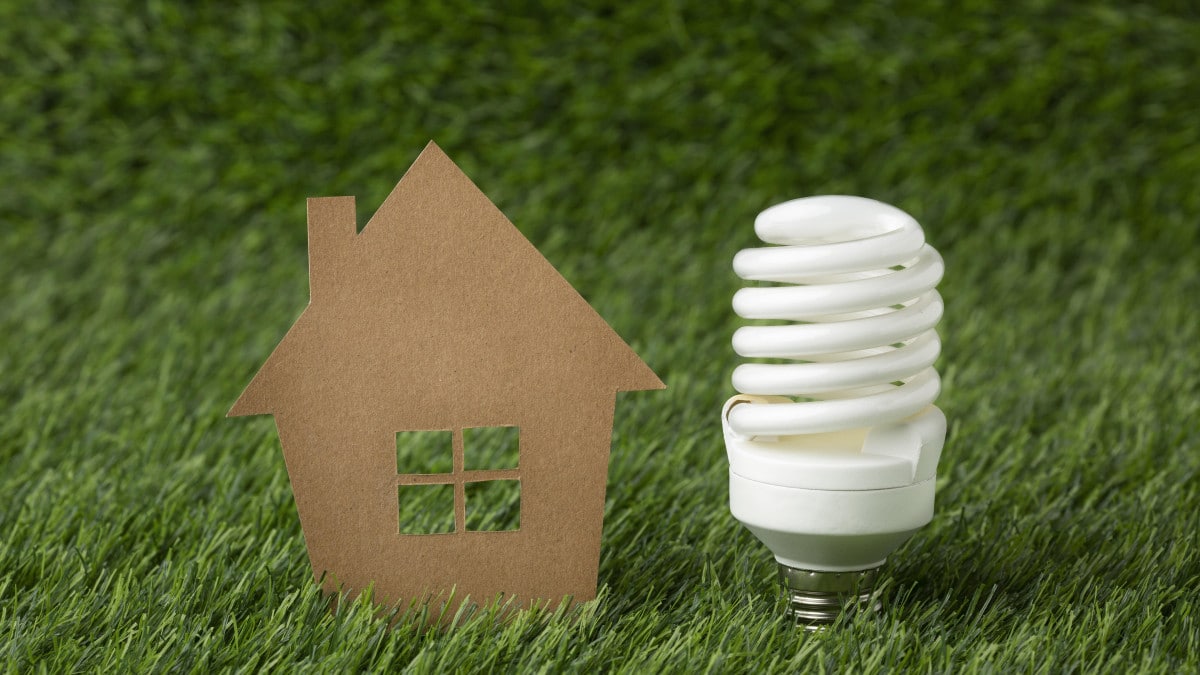 Une maison en carton accompagnée d'une ampoule démontrant le principe de transition énergétique